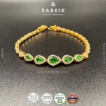 Close-up detail of gold plated 925 sterling silver bracelet featuring teardrop green synthetic stones and crystal accents