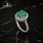 Emerald Ring crafted from authentic 925 Silver featuring a natural oval-cut emerald, sparkling cubic zirconia halo, rhodium plating and elegant shoulder detailing.