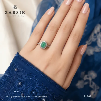 Woman wearing an Emerald Ring in 925 Silver with a natural oval-cut emerald, sparkling CZ halo and rhodium-plated finish for timeless elegance.